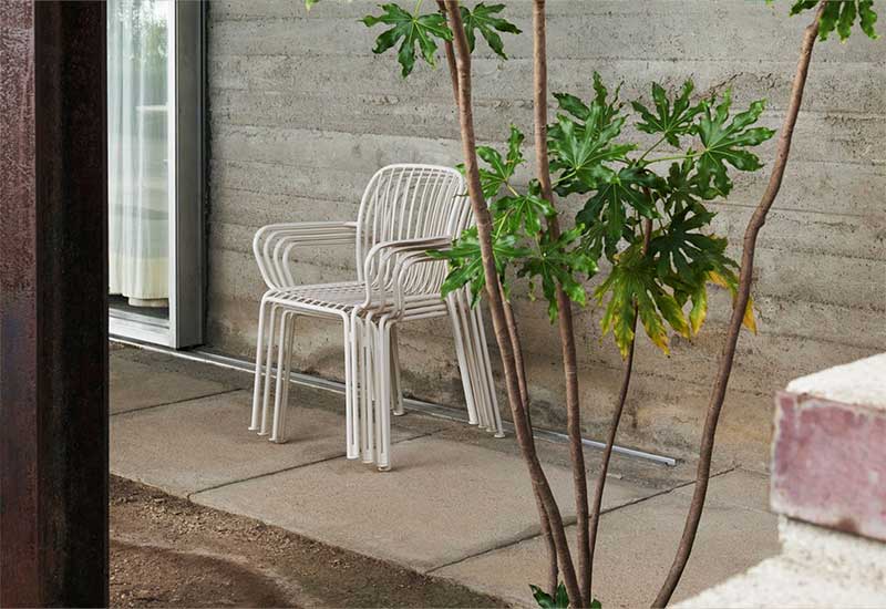 A stack of four Thorvald Armchairs by Space Copenhagen for &tradition in white positioned outside.