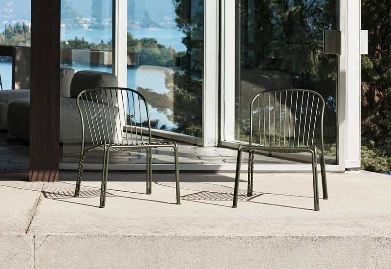 A pair of bronze green Thorvald Lounge Side Chairs by Space Copenhagen for &tradition, placed outside.