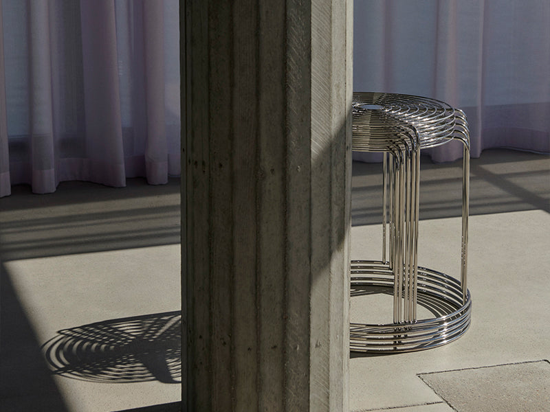 A stack of Wire Stools peering out from behind a column. The stool was designed by Verner Panton for &tradition.