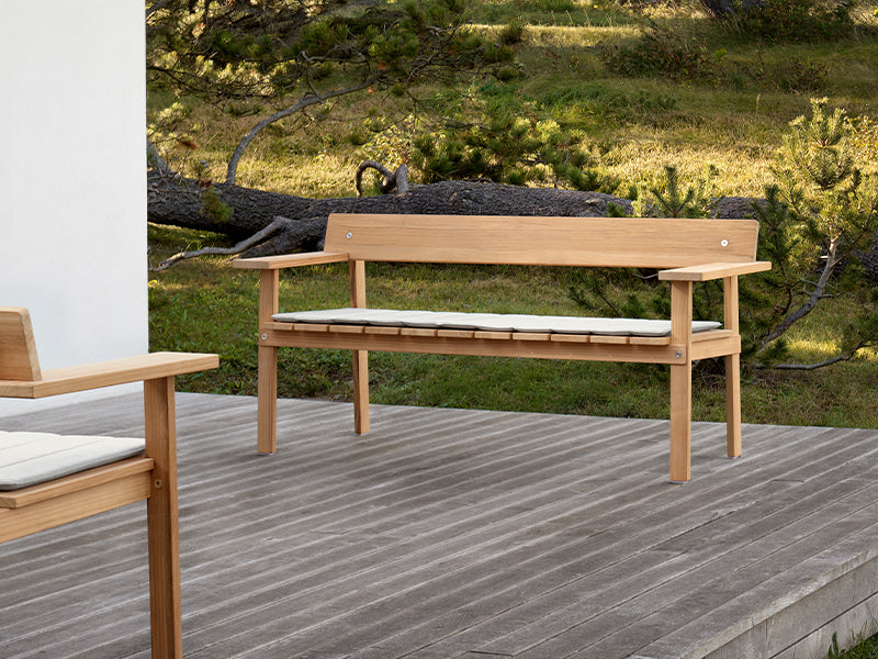 A cushioned GL101 Timbur Outdoor Bench, outside.