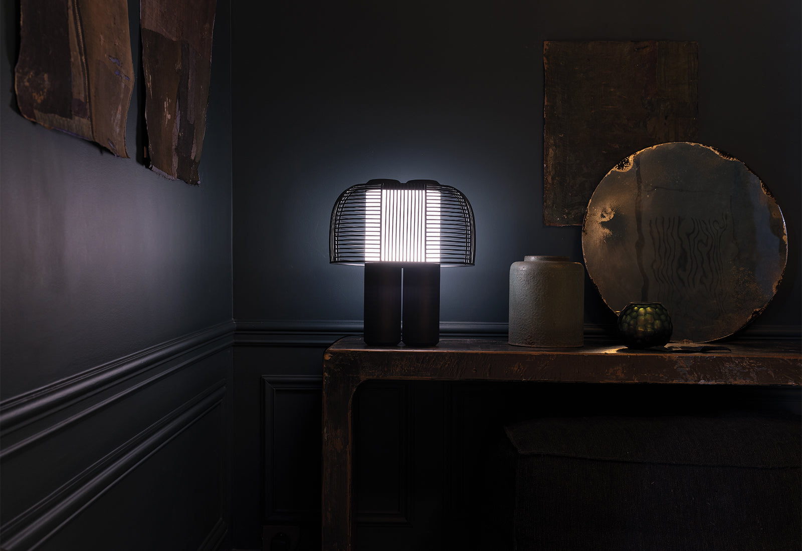 An illuminated Yasuke Table Lamp by Studio BrichetZiegler for DCW éditions on a wooden side table.