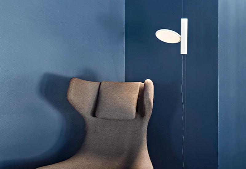 The Ok floor/pendant light in white placed in front of a blue wall.