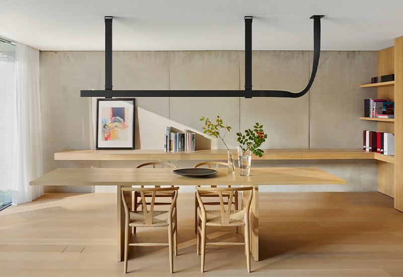  Designed by Ronan and Erwan Bouroullec for Flos, the Belt suspension light in black leather hangs above a large dining table.