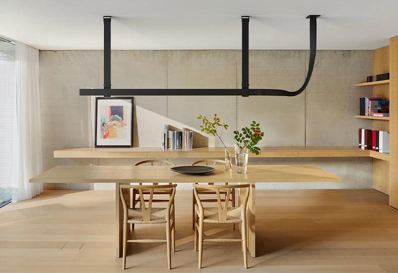 Designed by Ronan and Erwan Bouroullec for Flos, the Belt suspension light in black leather hangs above a large dining table.