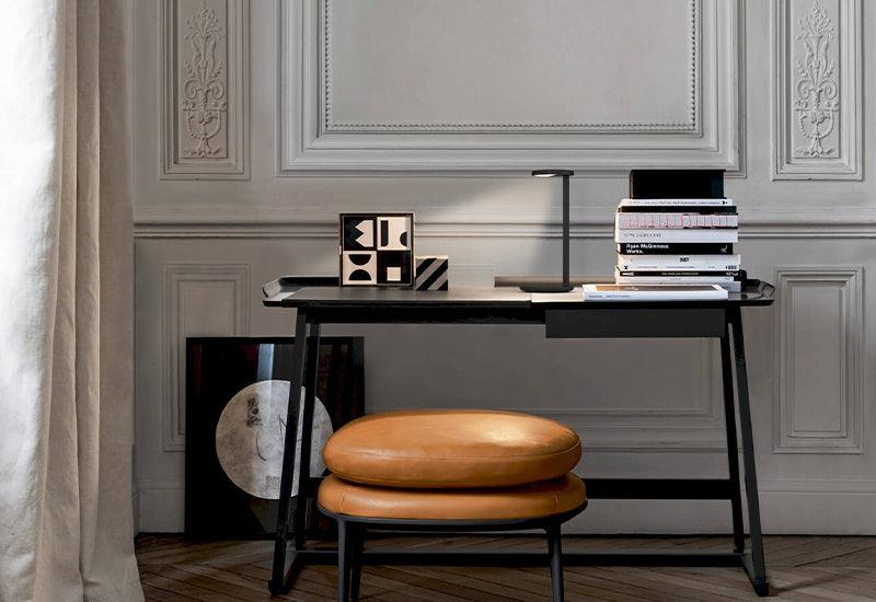 The Oblique lamp, by Vincent van Duysen for Flos, black. The lamp is placed on a blackdesk.