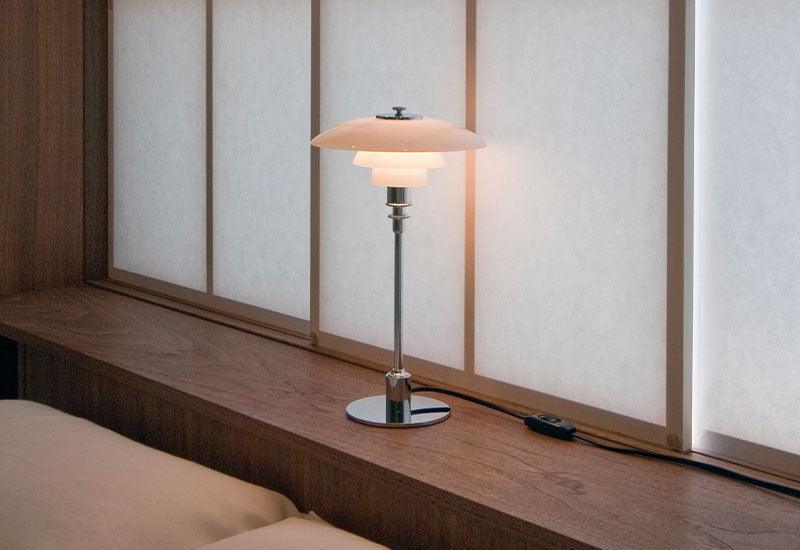 PH 2/1 table light by Poul Henningsen for Louis Poulsen on a shelf above a bed.