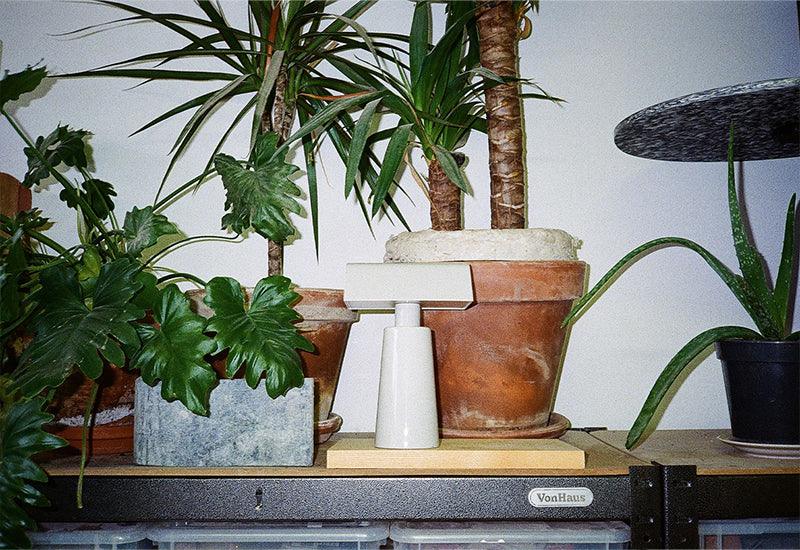 The Caret portable light by Mateo Fogale for &tradition in silk grey displayed with some plants.