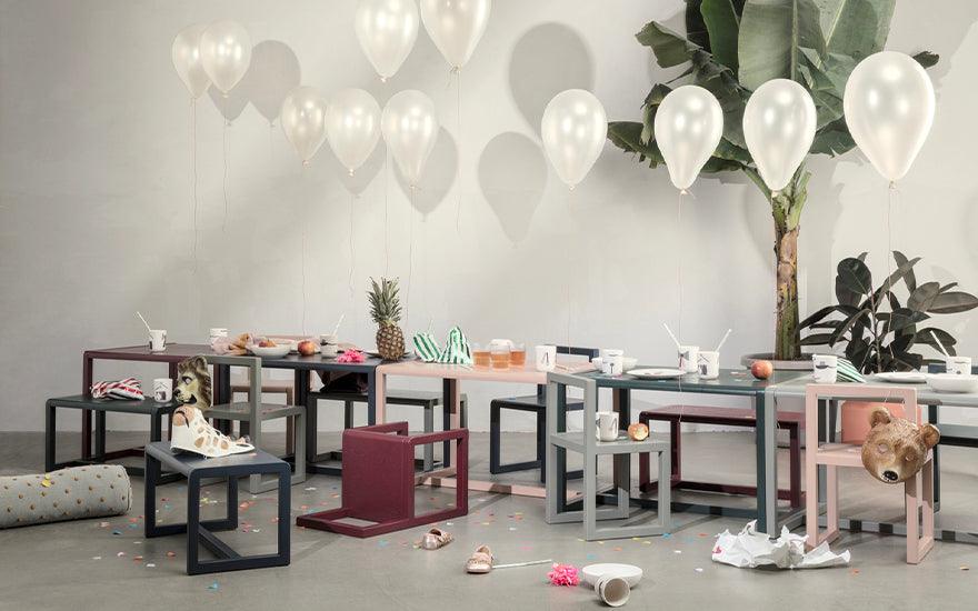  A row of Ferm Living Architect Tables in various colours featured in an empty party scene.
