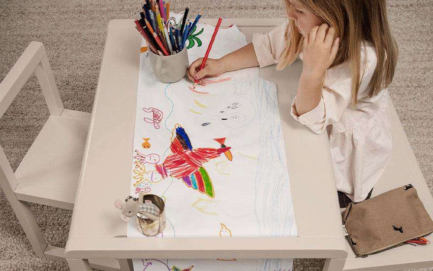  A child sits drawing at a Ferm Living Architect Table in grey.