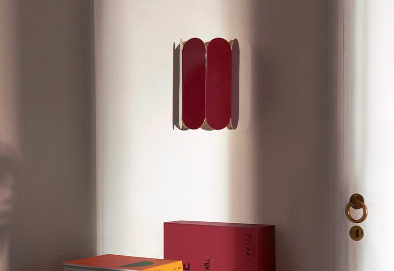  Designed by Muller Van Severen for HAY, the Arcs wall light in auburn red, displayed in an interior setting.