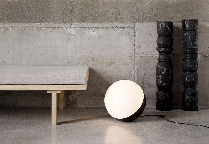  The VL Studio Table/Floor Light ﻿by ﻿Vihlem Lauritzen ﻿for ﻿Louis Poulsen in black beside a bench.
